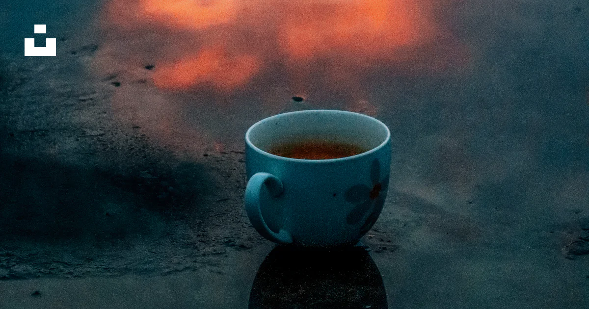 A cup of tea sitting on top of a puddle of water photo – Free Cup Image ...