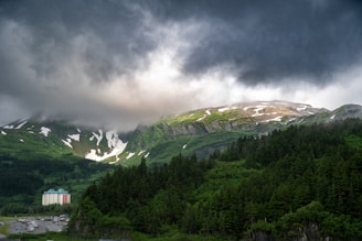 A cloudy sky over a mountain with a house in the foreground
