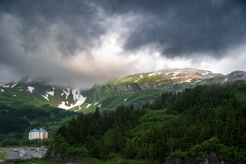 A cloudy sky over a mountain with a house in the foreground
