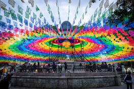 A large multicolored display of flags in front of a building