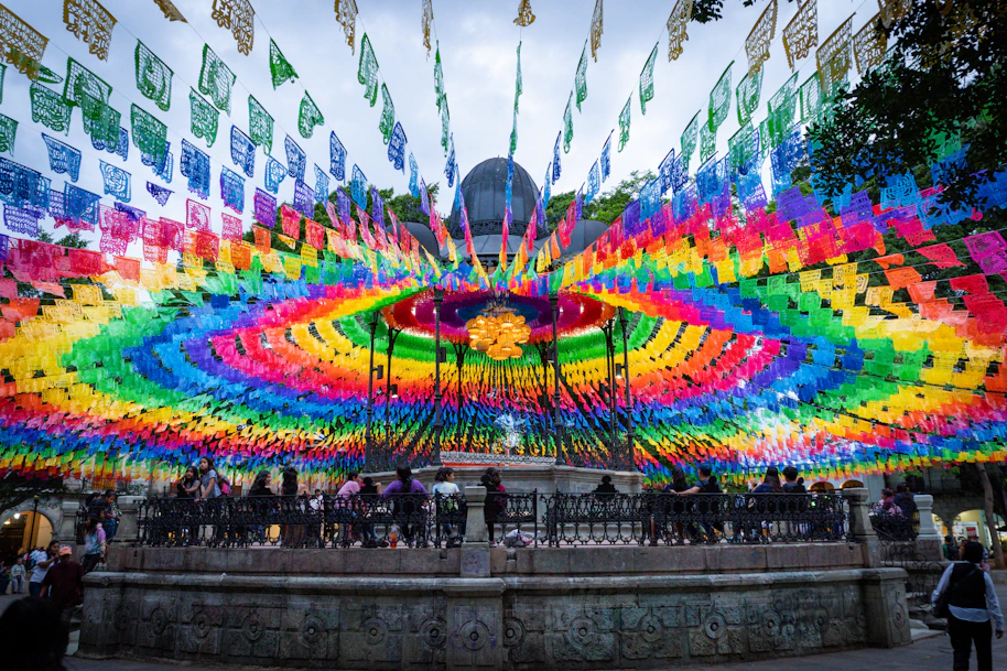 A large multicolored display of flags in front of a building
