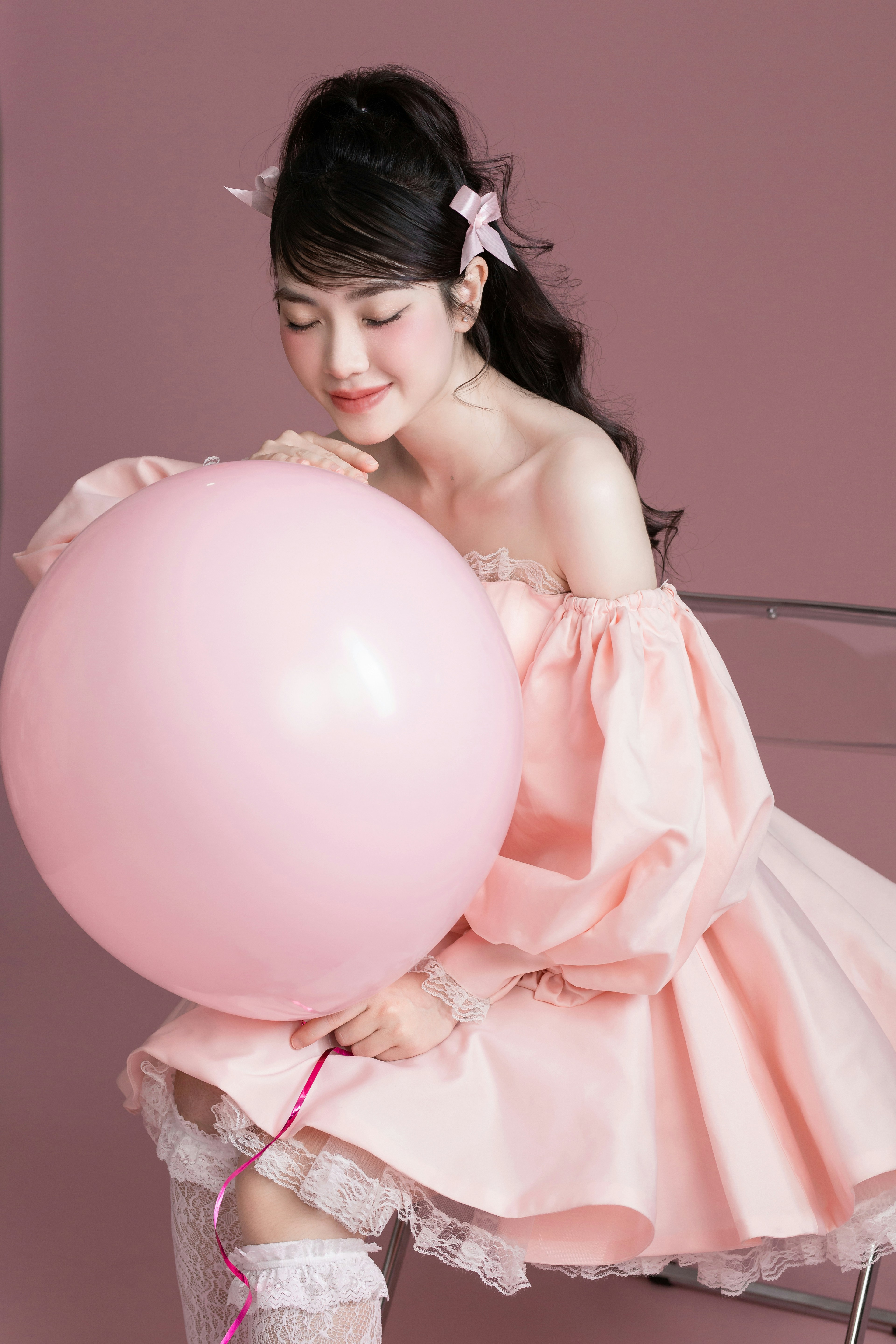 A woman in a pink dress holding a pink balloon