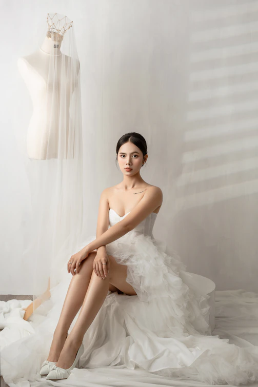 A woman in a white dress sitting on a bed