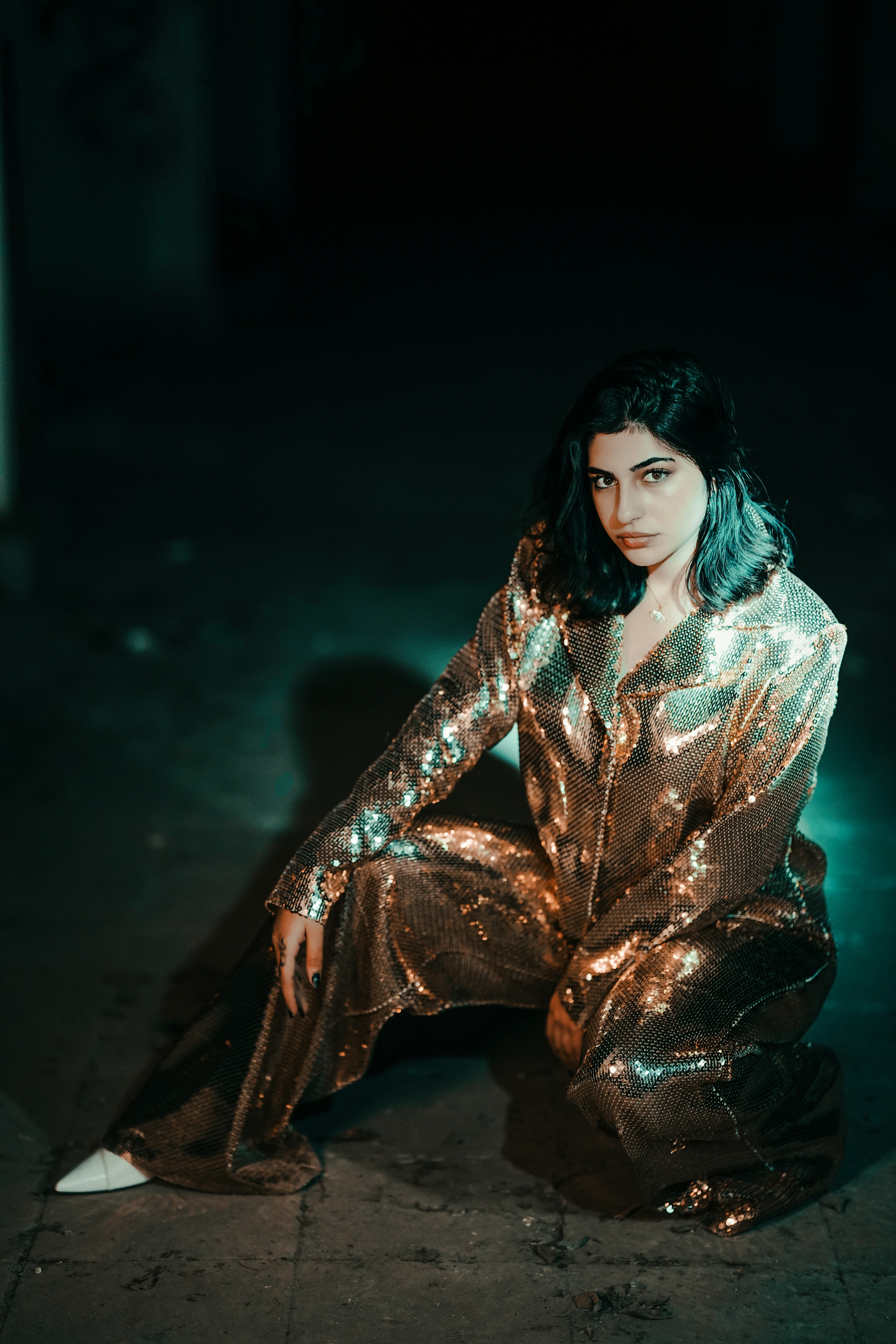 A woman sitting on the ground in a shiny outfit