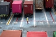 A man standing in a parking lot next to lots of shipping containers