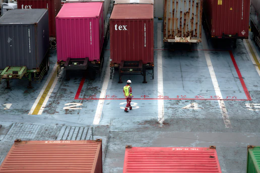 A man standing in a parking lot next to lots of shipping containers