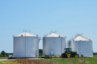 A tractor is parked in front of three silos
