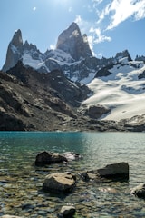 A lake surrounded by rocks and snow covered mountains