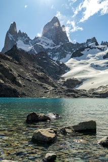 A lake surrounded by rocks and snow covered mountains