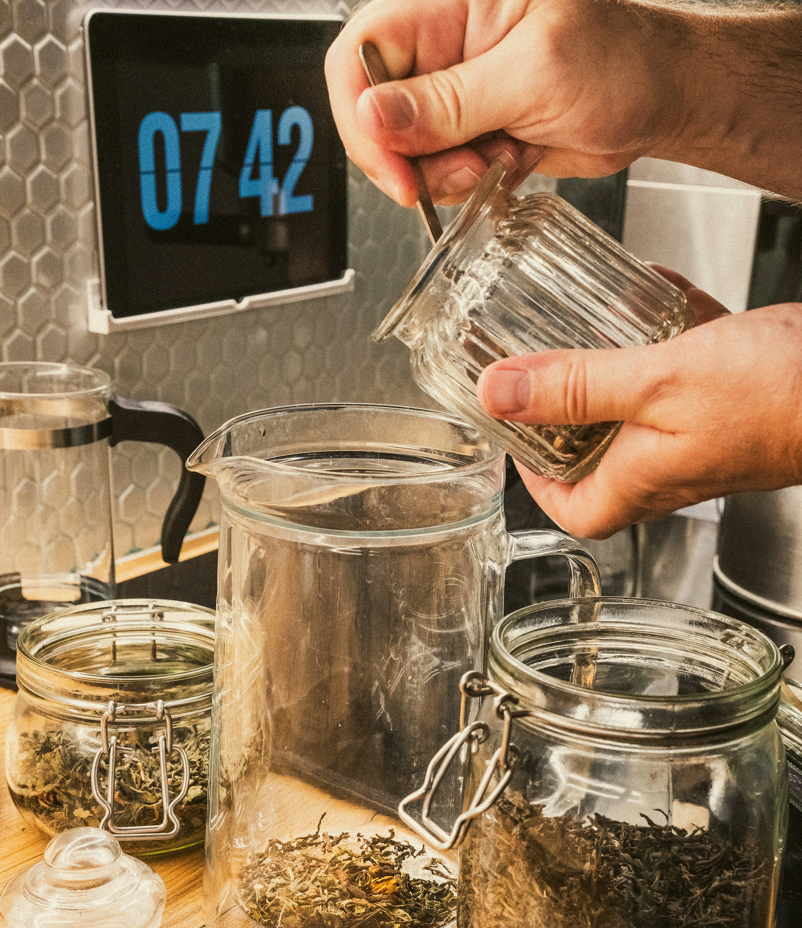 A person pours a cup of tea into a jar