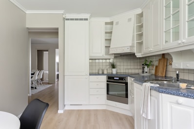 A kitchen with white cabinets and wooden floors