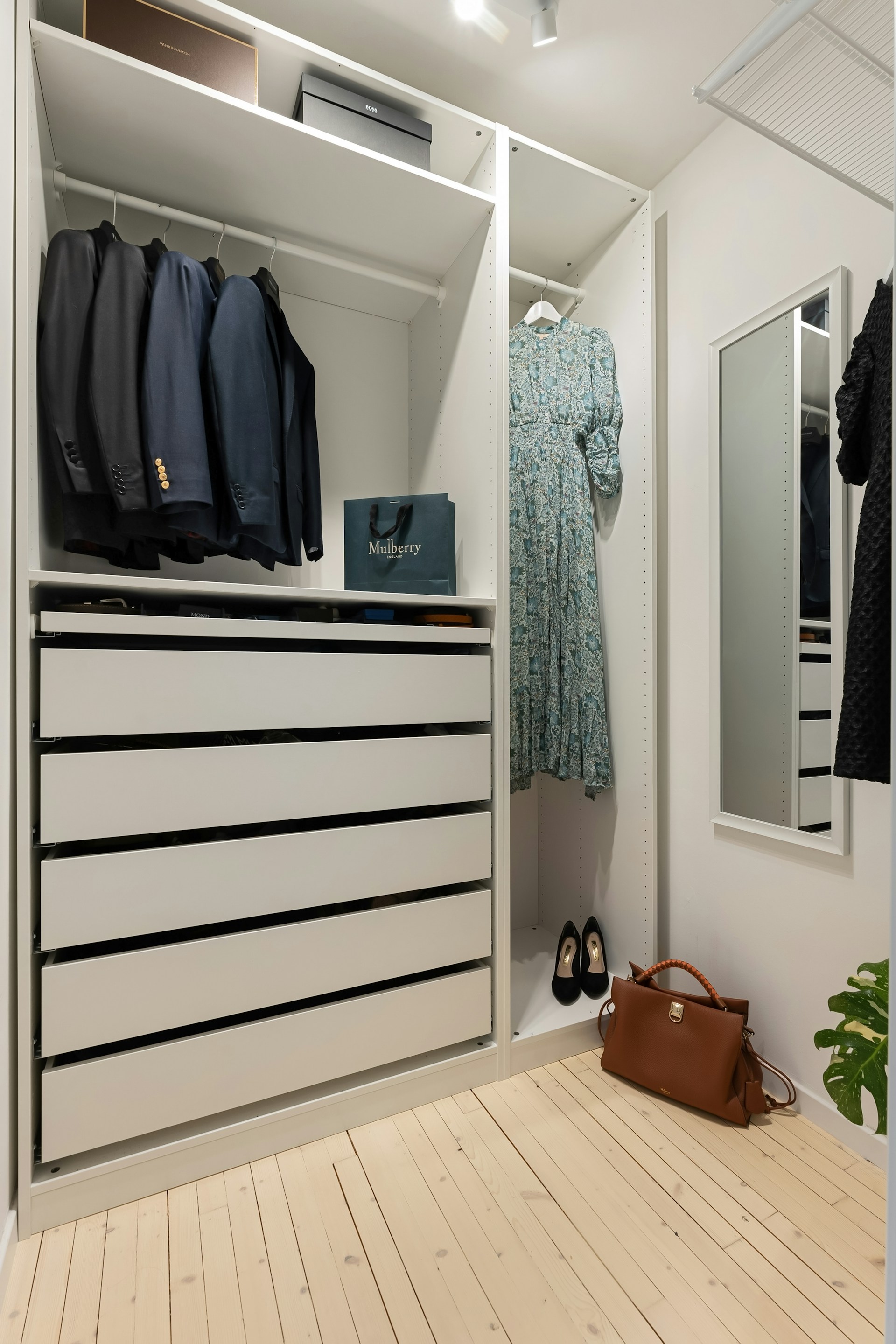 A walk in closet with clothes and a handbag