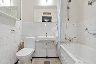 A white bathroom with a tub, toilet and sink