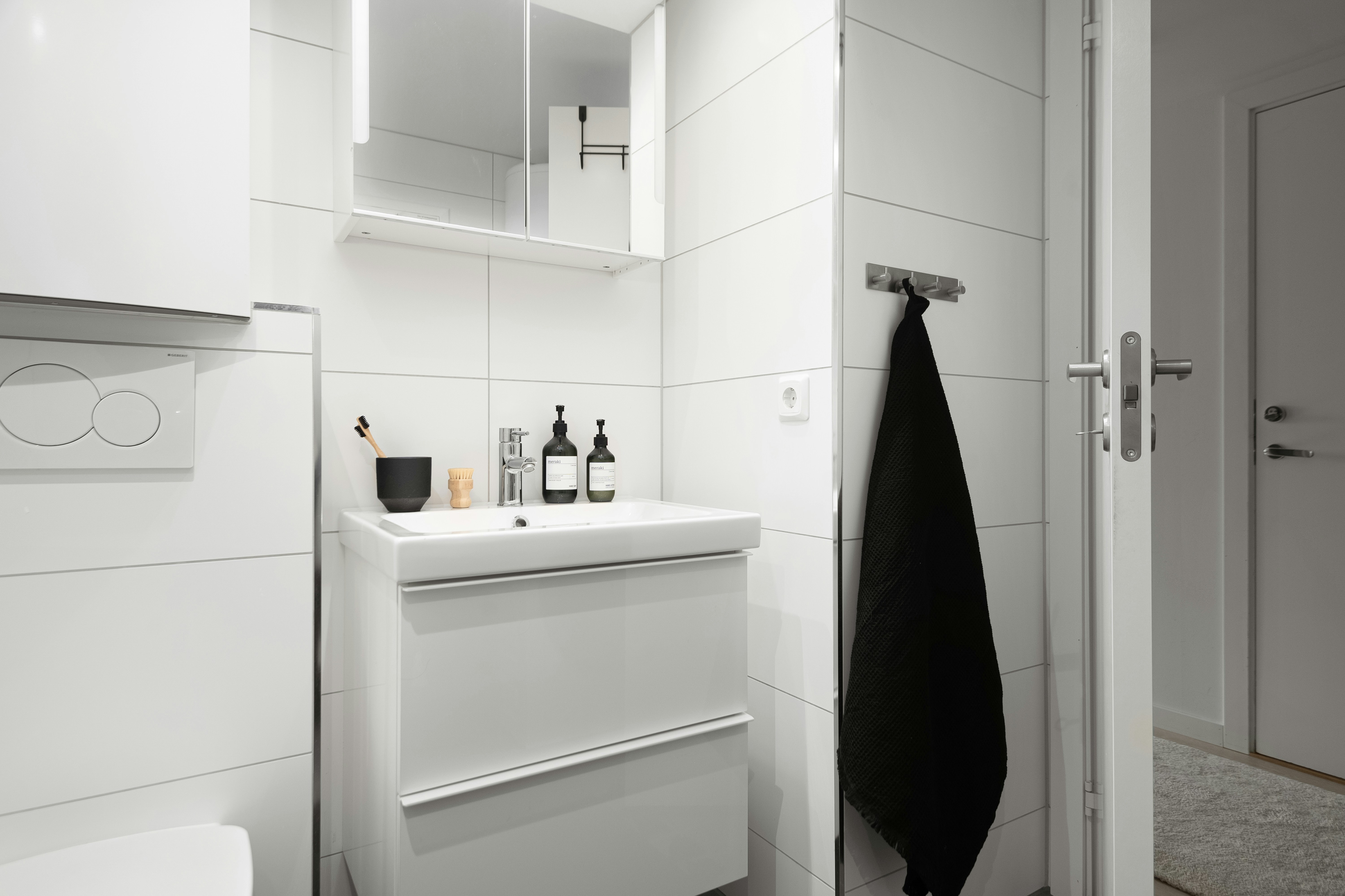 A white bathroom with a black towel hanging on the wall