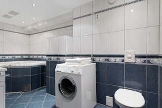 A washer and dryer in a bathroom with blue tile