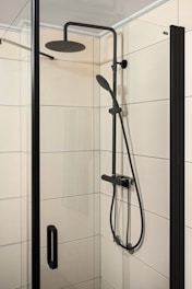 A walk in shower sitting next to a white tiled wall