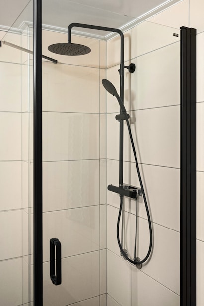 A walk in shower sitting next to a white tiled wall