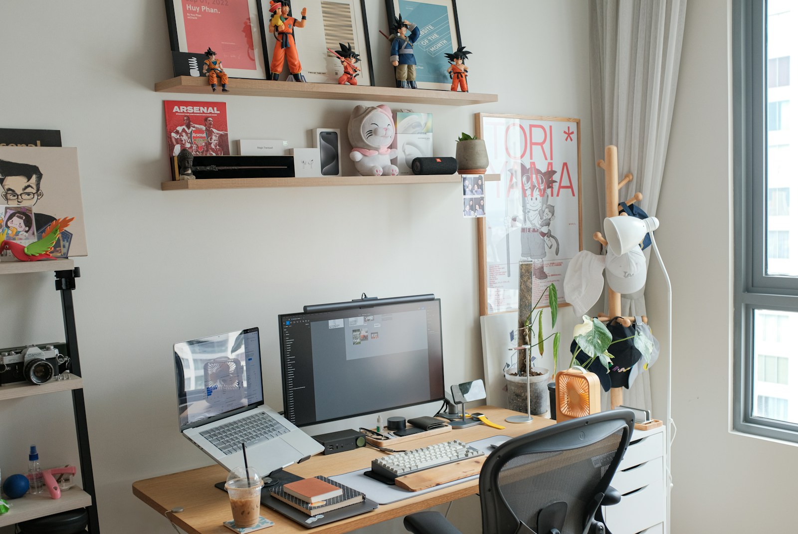 young professional desk with monitor laptop and shelf of figurines and posters