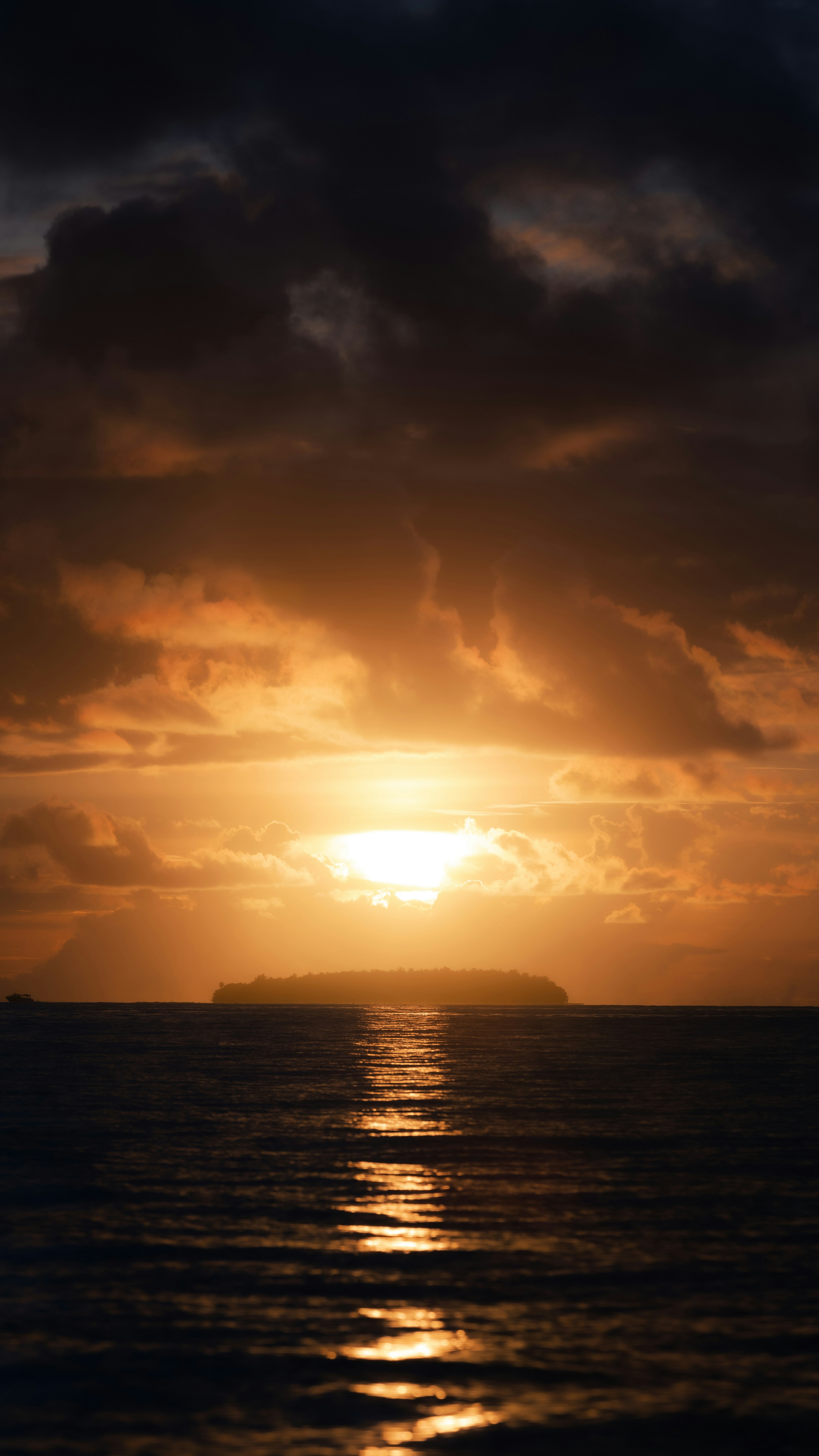 A small island silhouette on the horizon under a bright golden hour sky