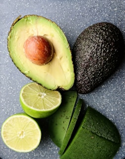 An avocado, lime, and lime slices on a table