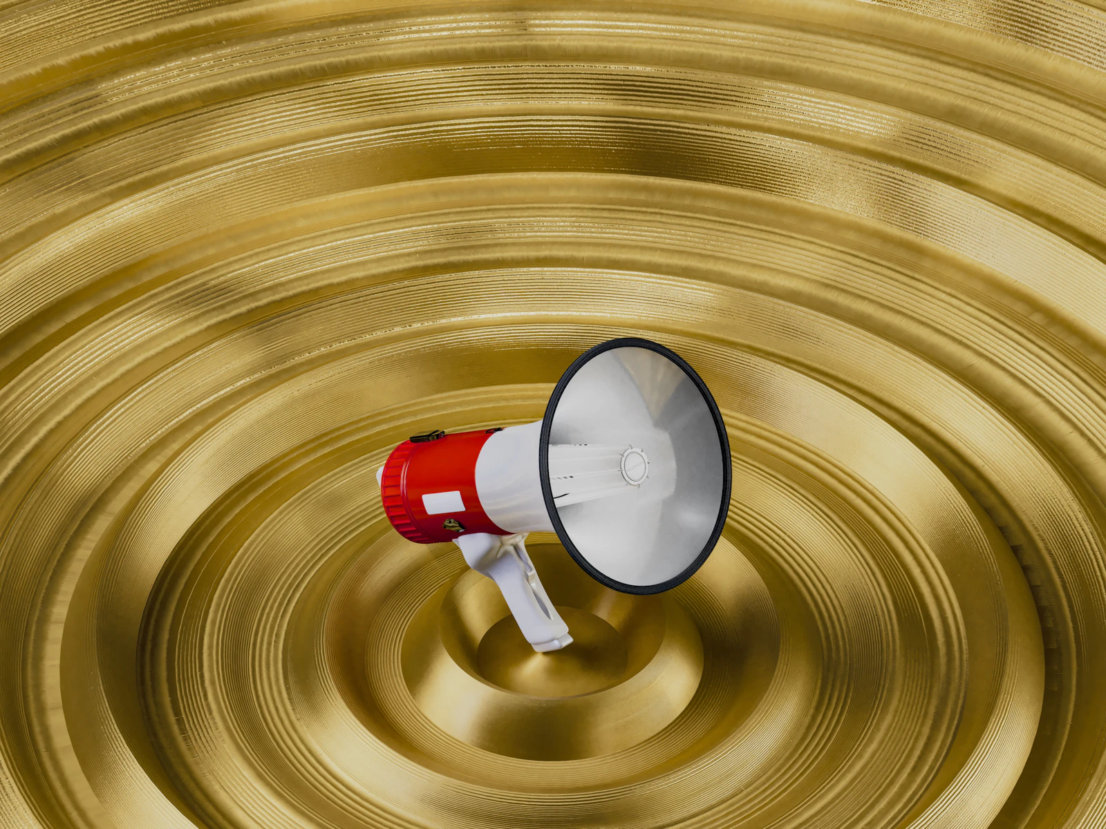 A red and white bullhorn resting in a rippled golden bowl