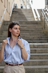 A woman in a blue shirt and khaki pants is standing on the steps