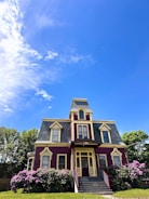 A large purple house sitting on top of a lush green field