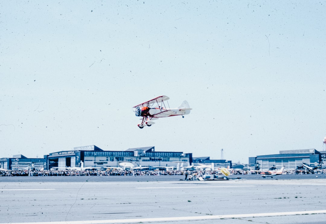 A small plane is flying low over a runway,