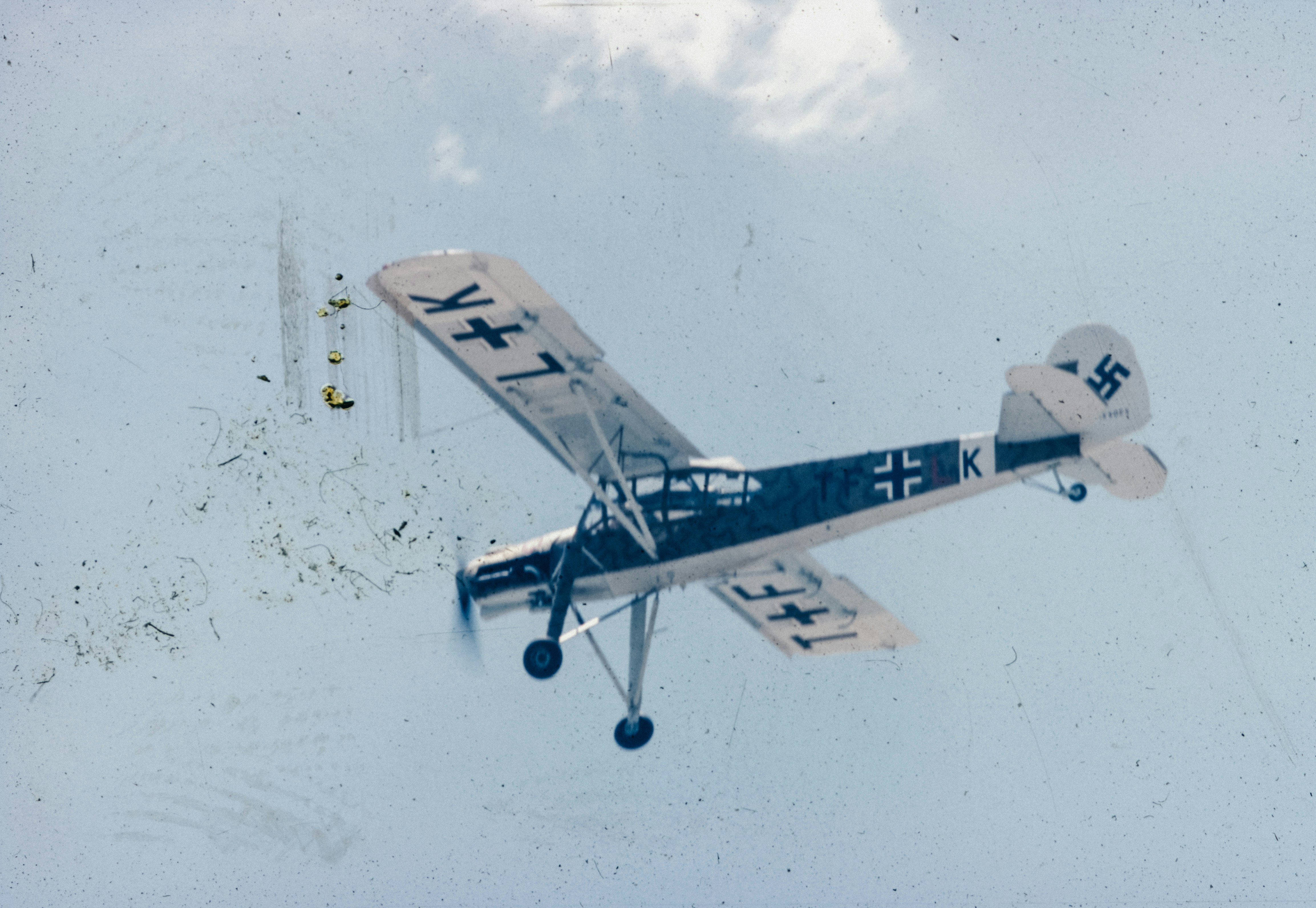 A small airplane flying through a cloudy blue sky, 