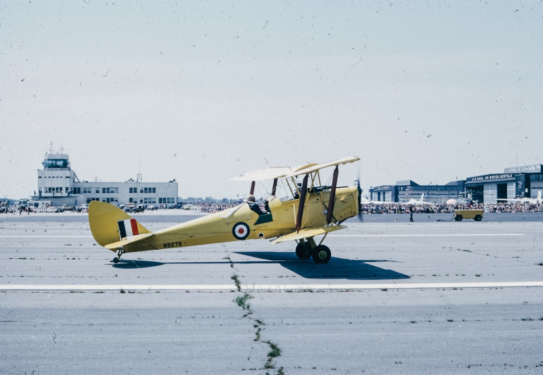 A small yellow airplane sitting on top of an airport tarmac,
