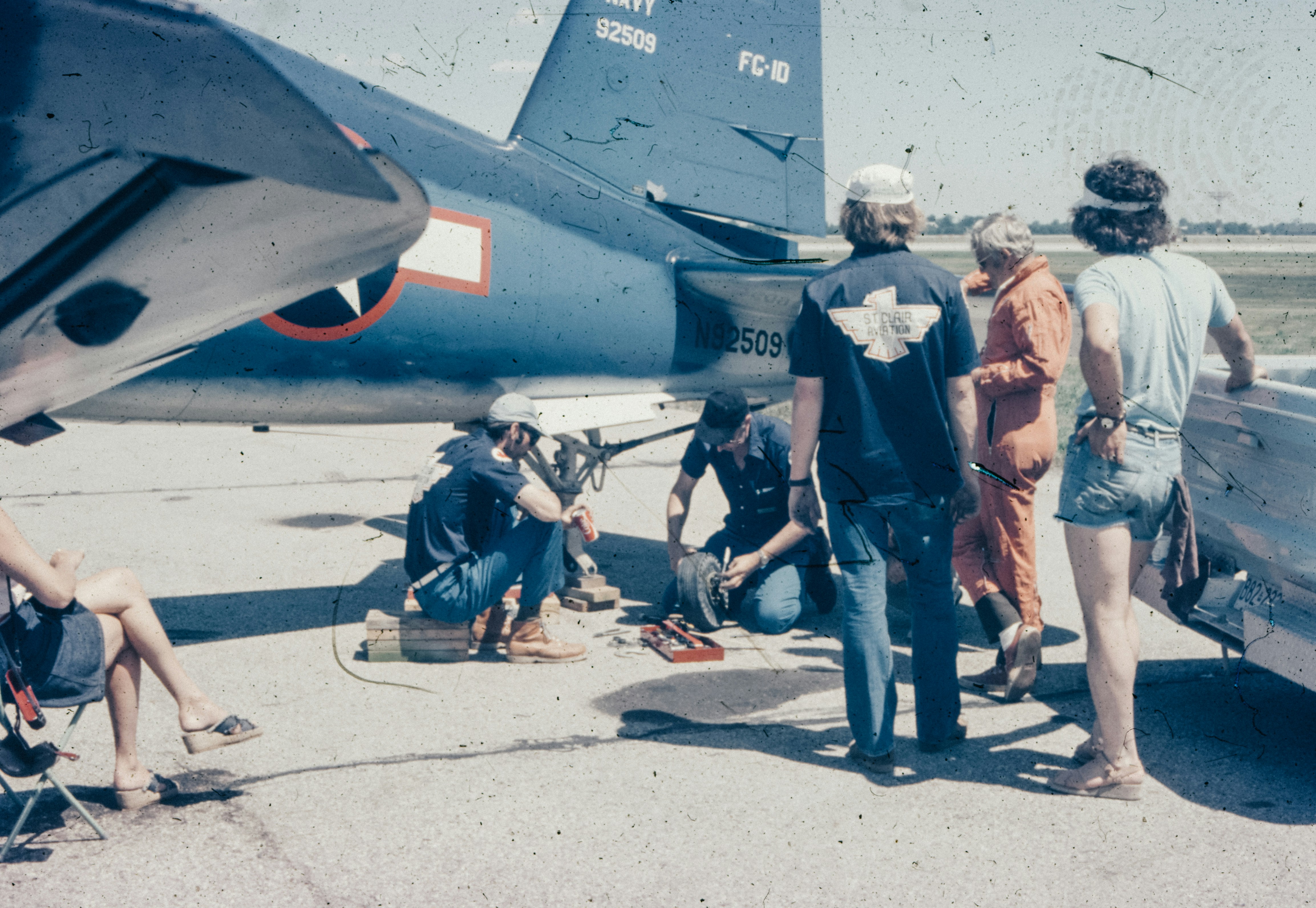 A group of people standing around a parked airplane, 