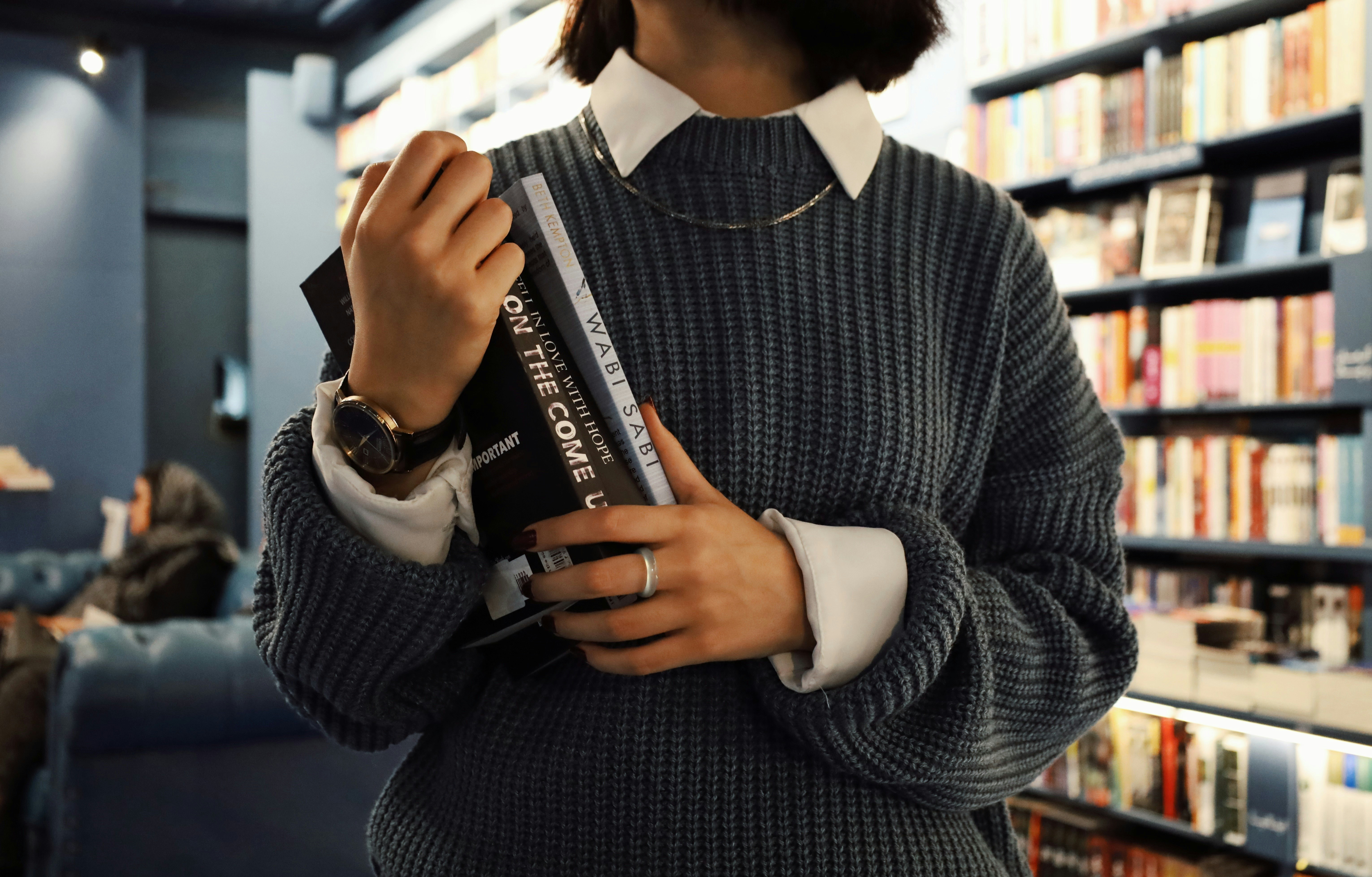 A woman standing in a library holding a book