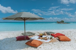 An umbrella and some pillows on a beach