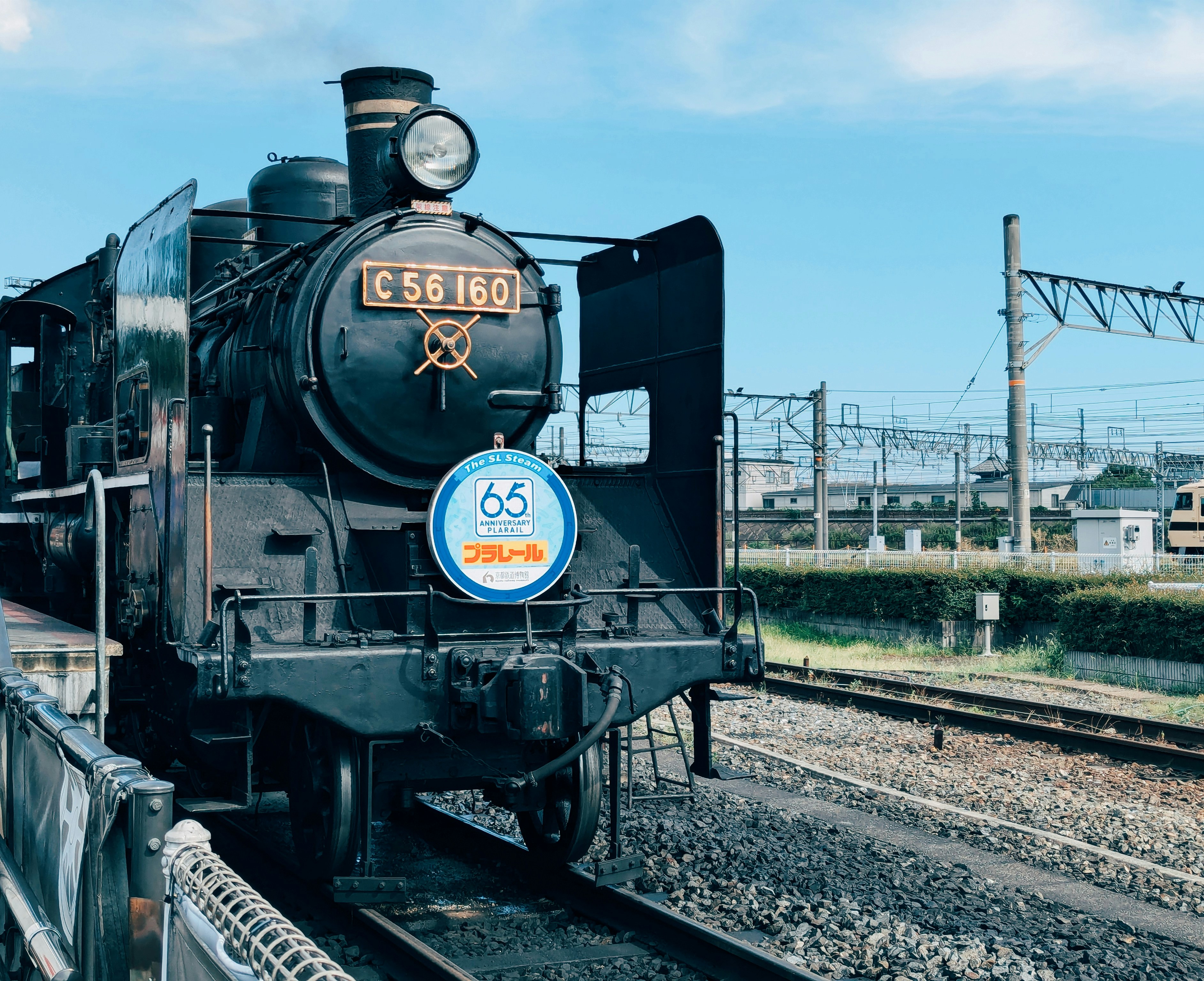 A black train traveling down train tracks next to a field