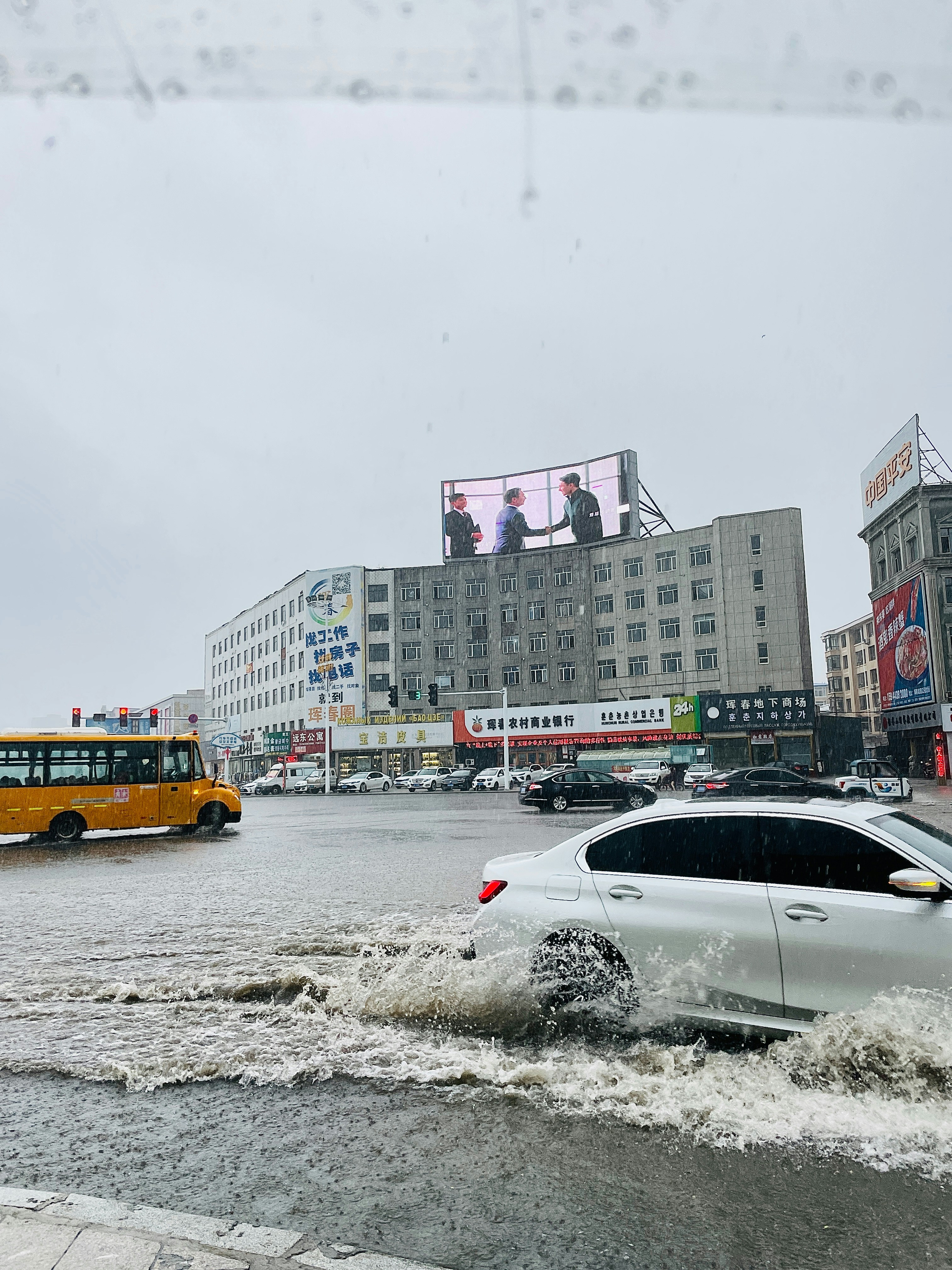 A car is driving through a flooded street