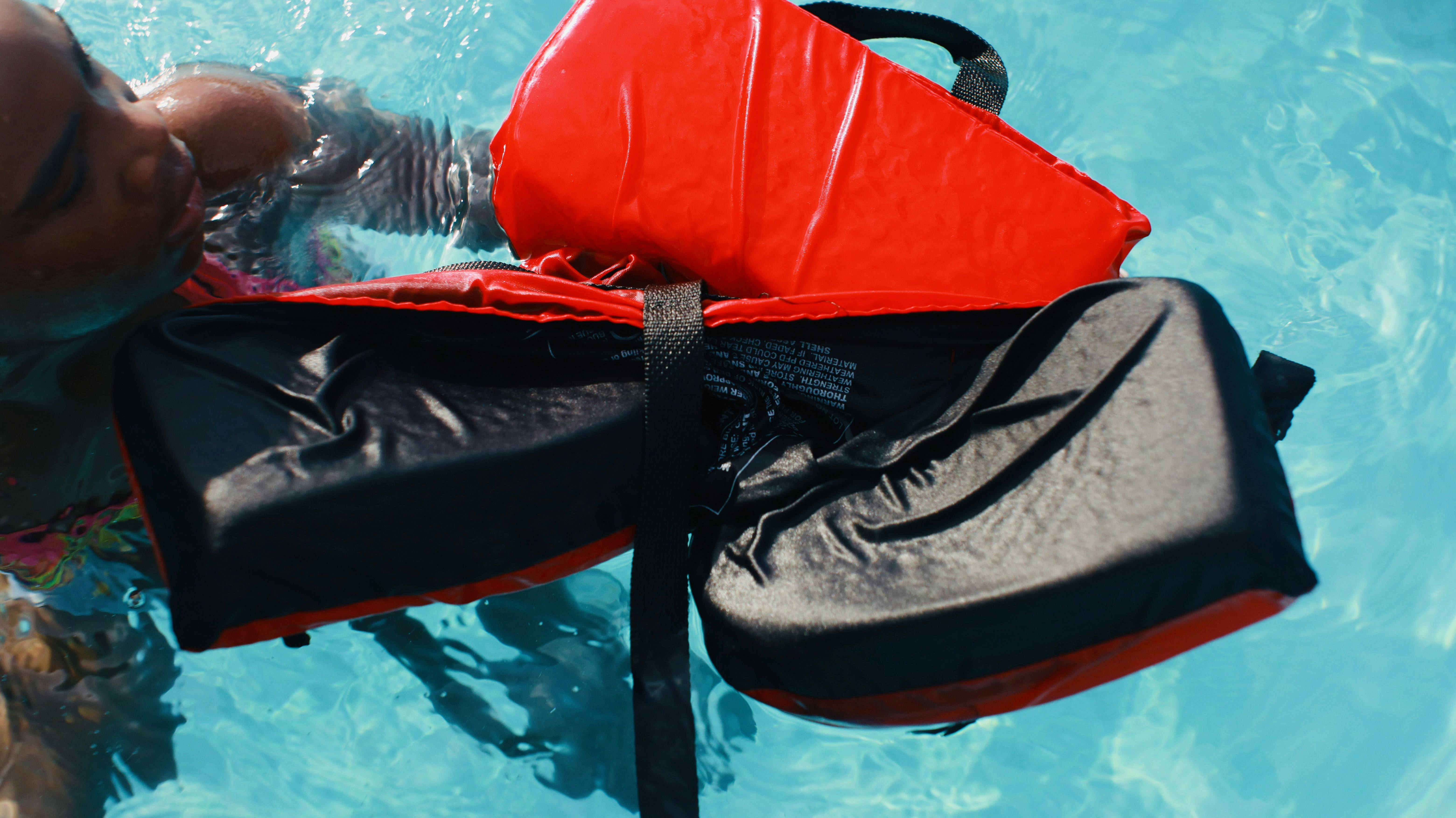 A man swimming in a pool with a life jacket on
