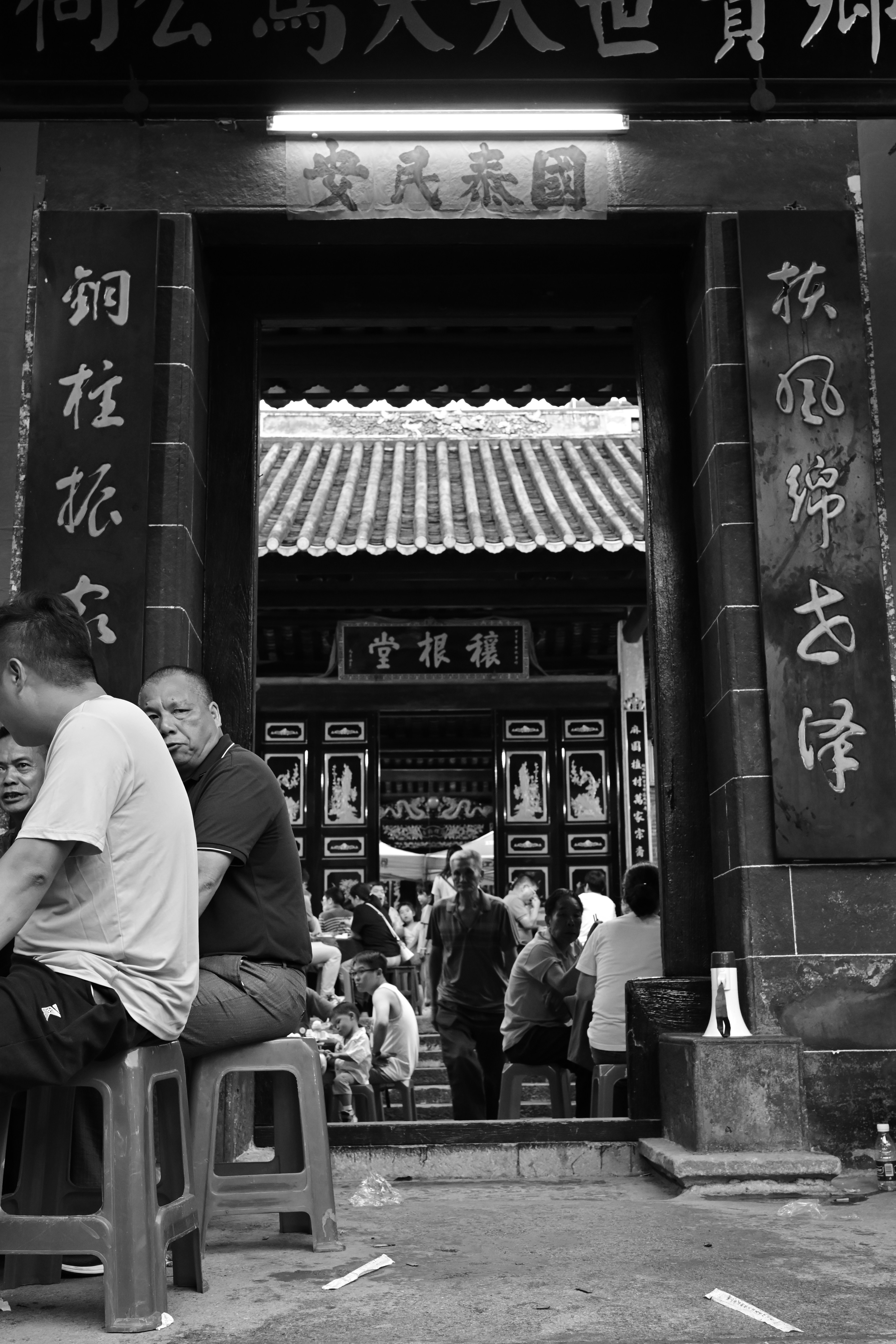 Two men sitting on stools in front of a building