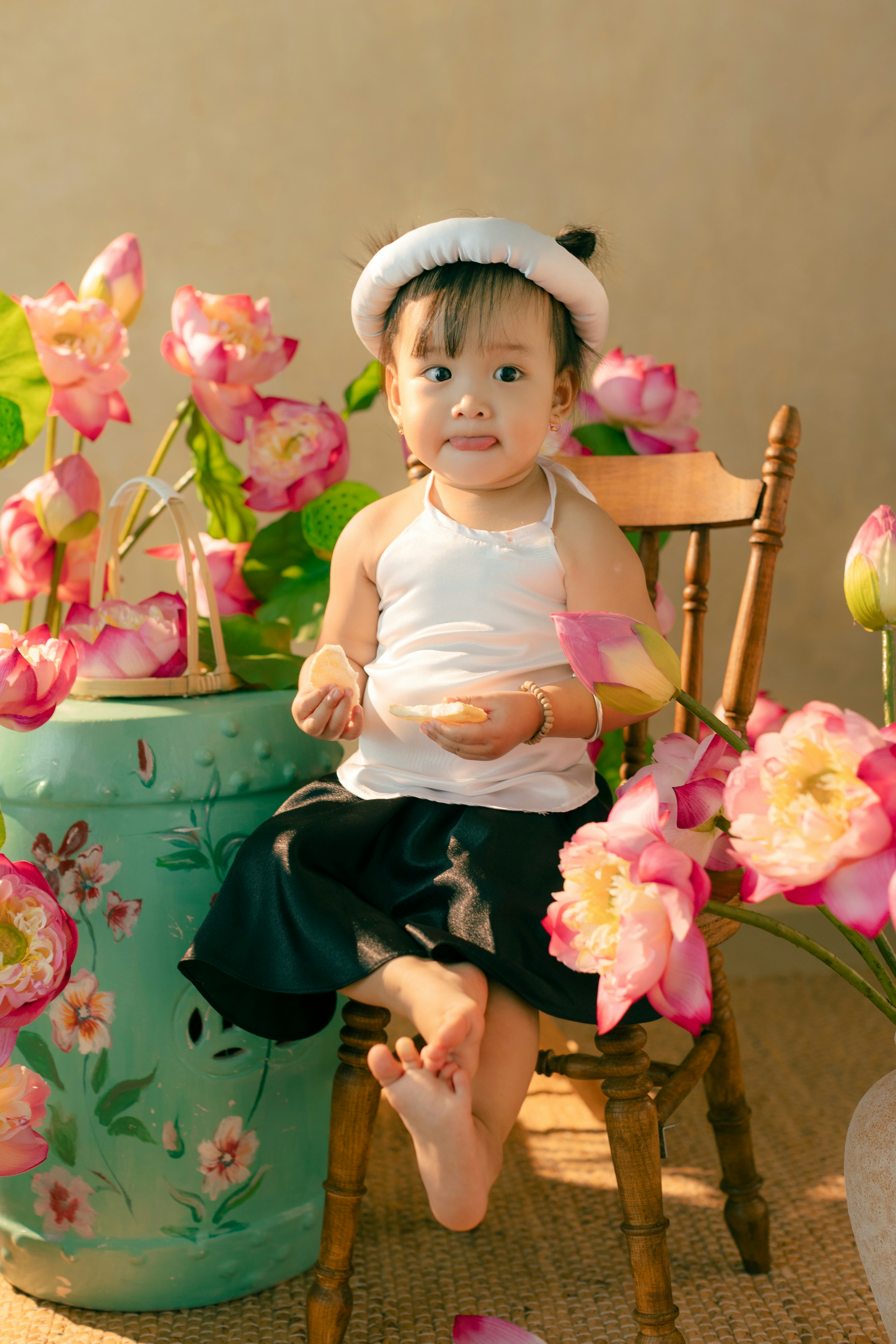 A little girl sitting in a chair next to a flower pot