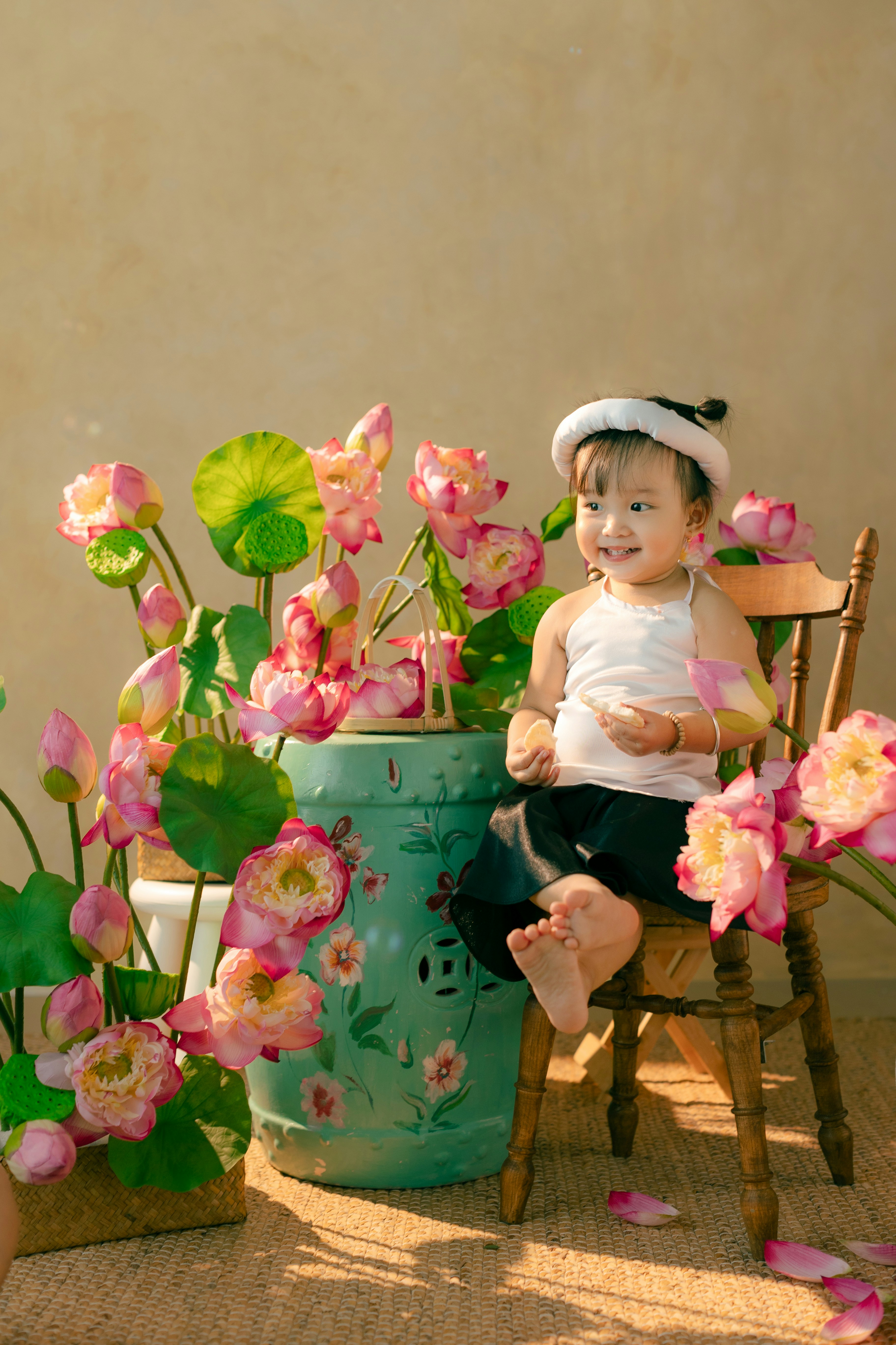 A little girl sitting on a chair next to a potted plant