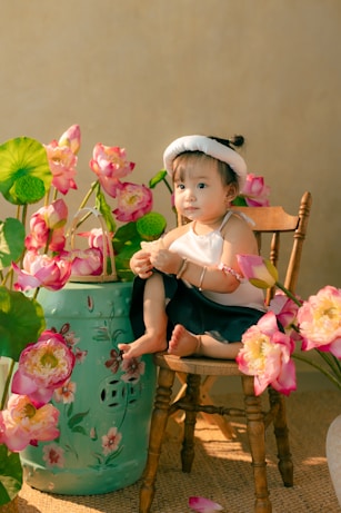 A little girl sitting in a chair next to a potted plant