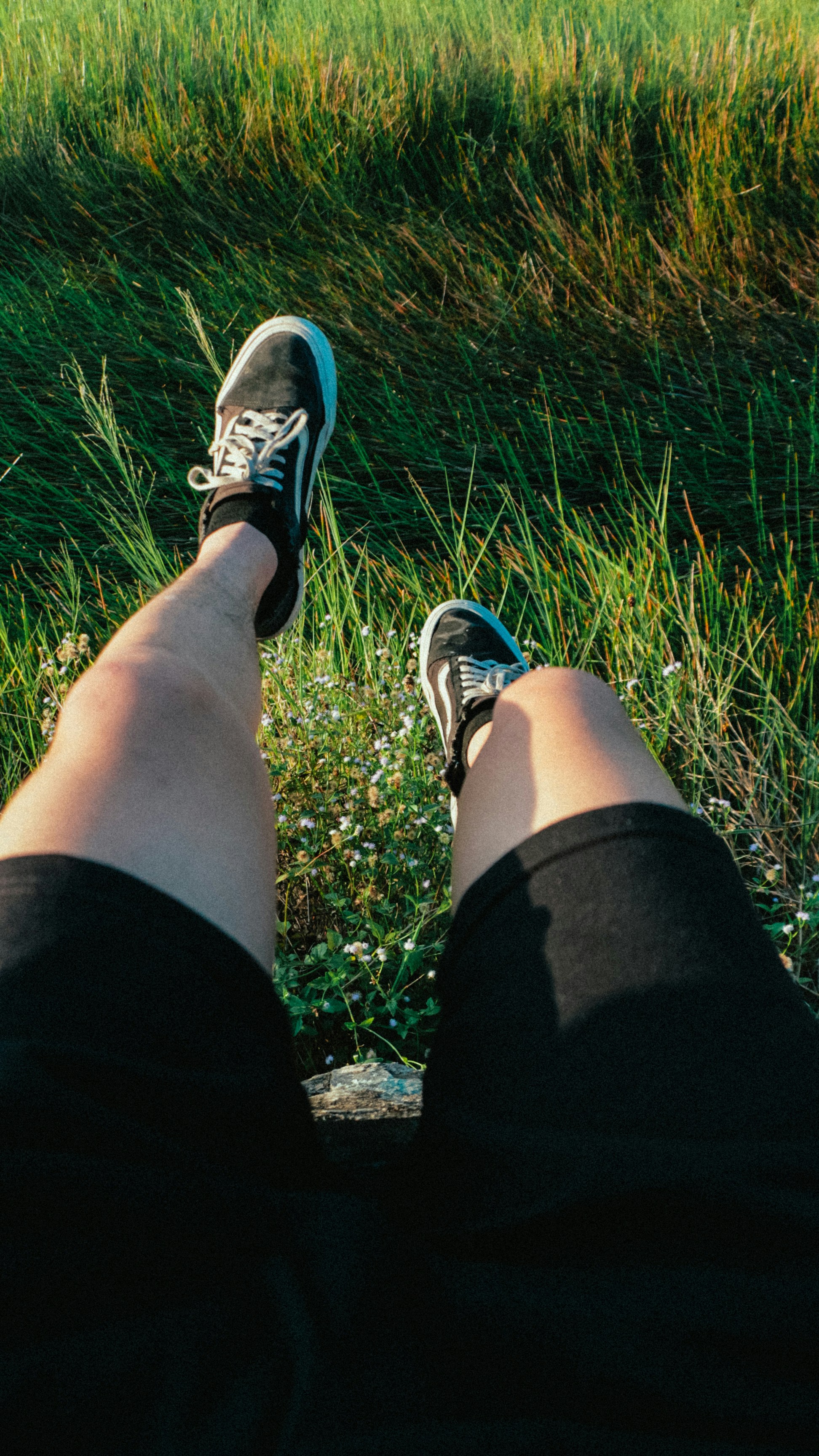 A person is sitting in the grass with their legs crossed