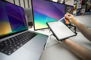 A person sitting at a desk with a laptop and a monitor