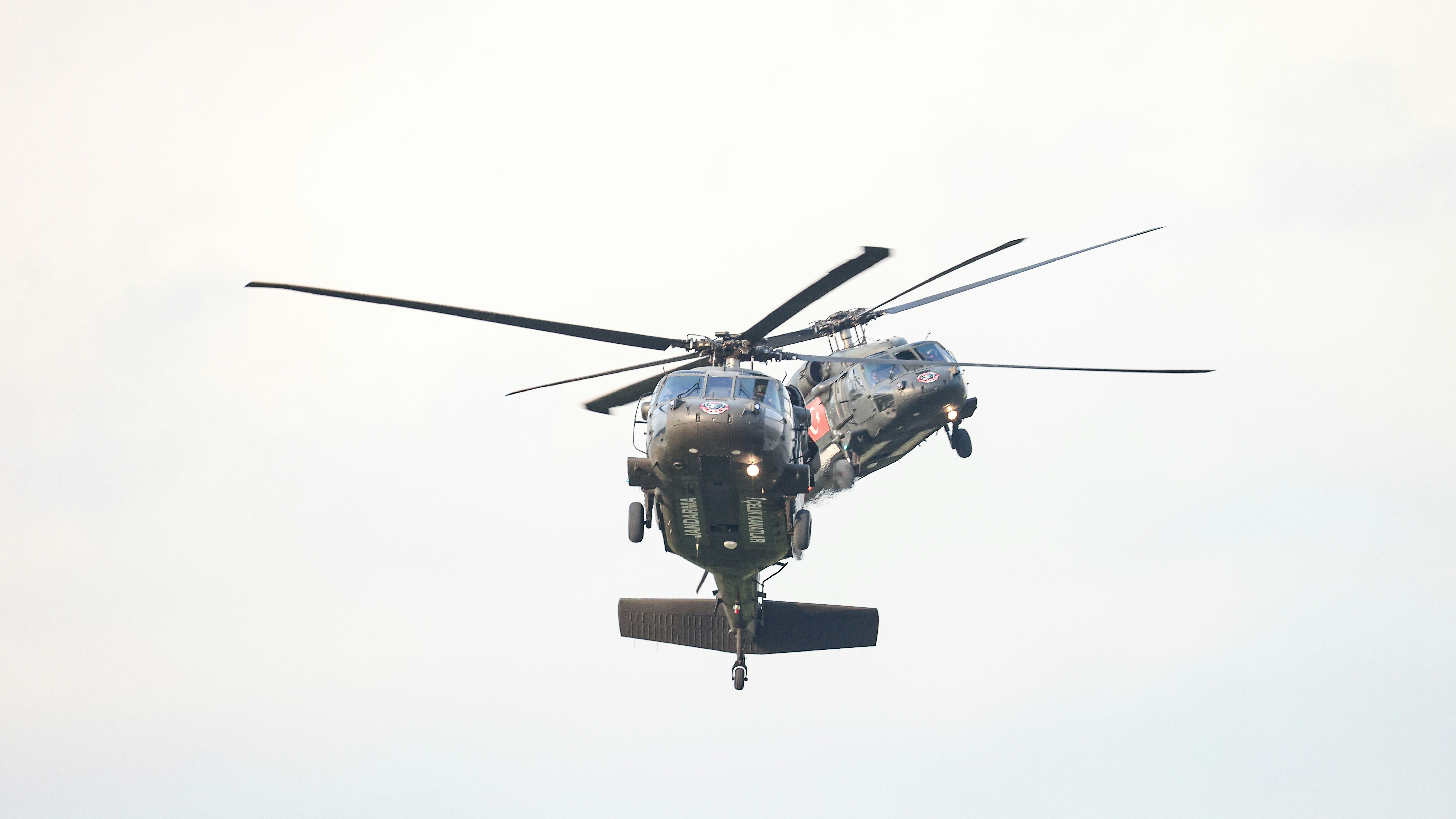 A helicopter is flying in the sky with its landing gear down