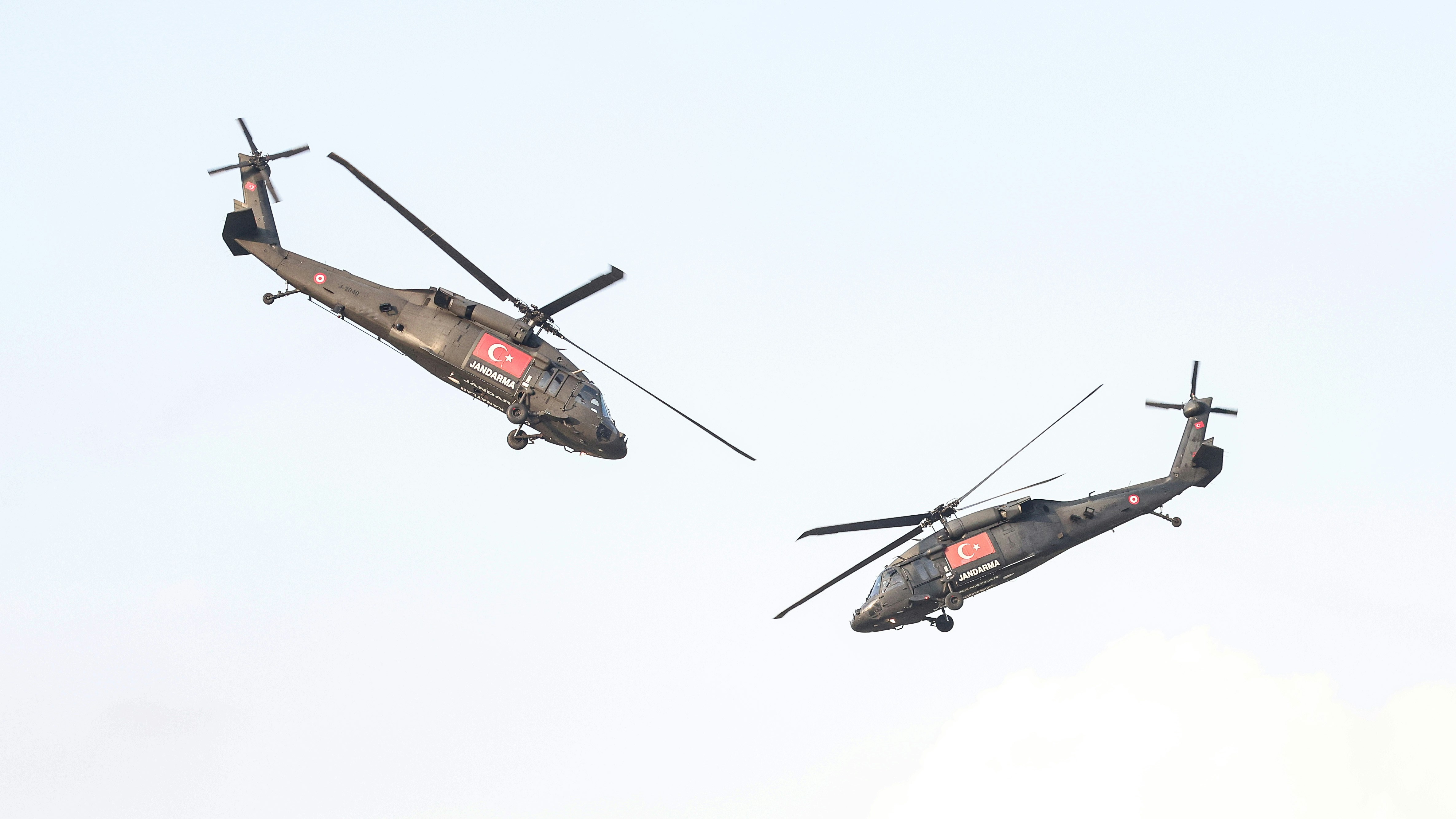 A couple of helicopter flying through a blue sky