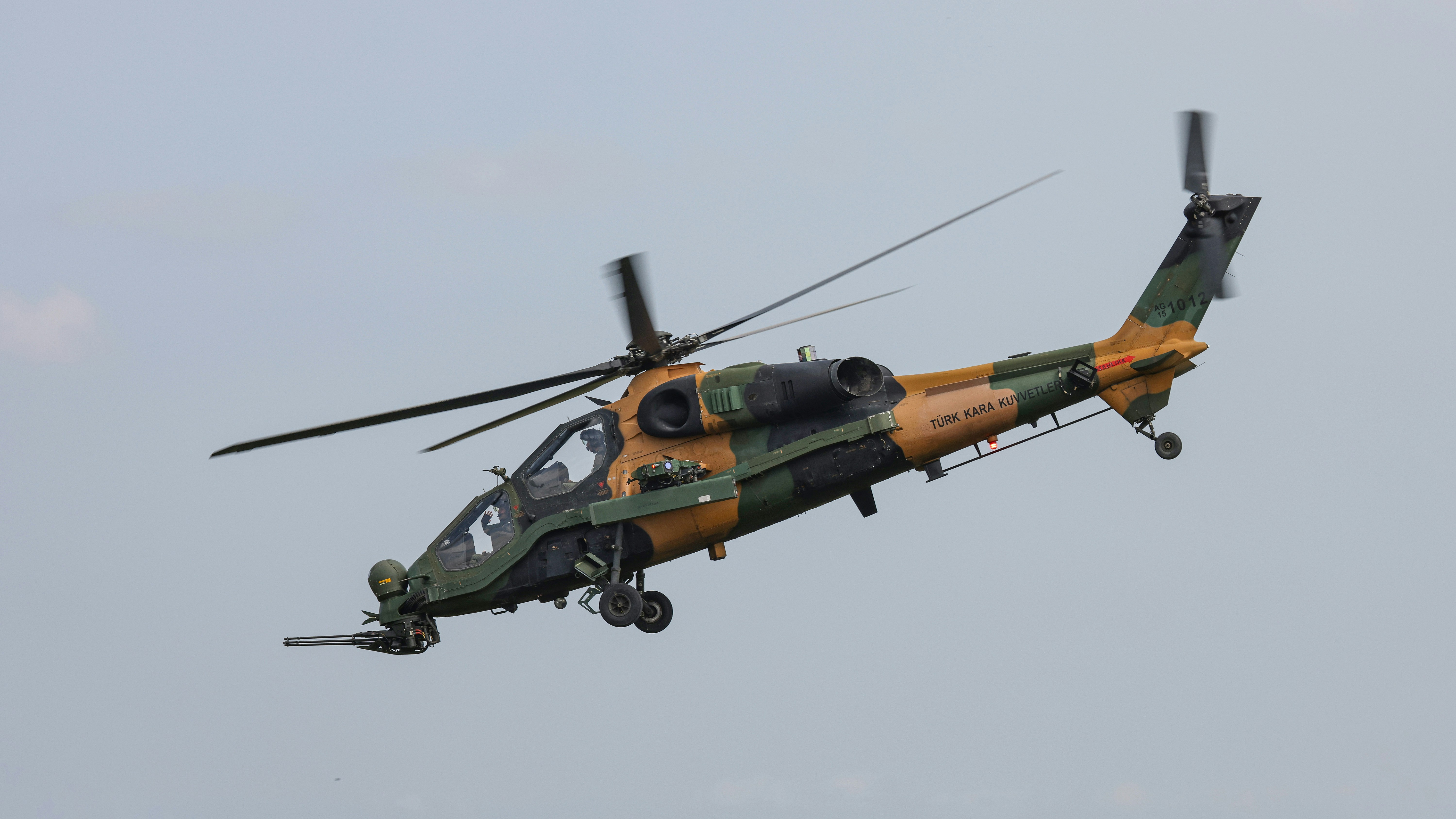 A green and yellow helicopter flying in the sky