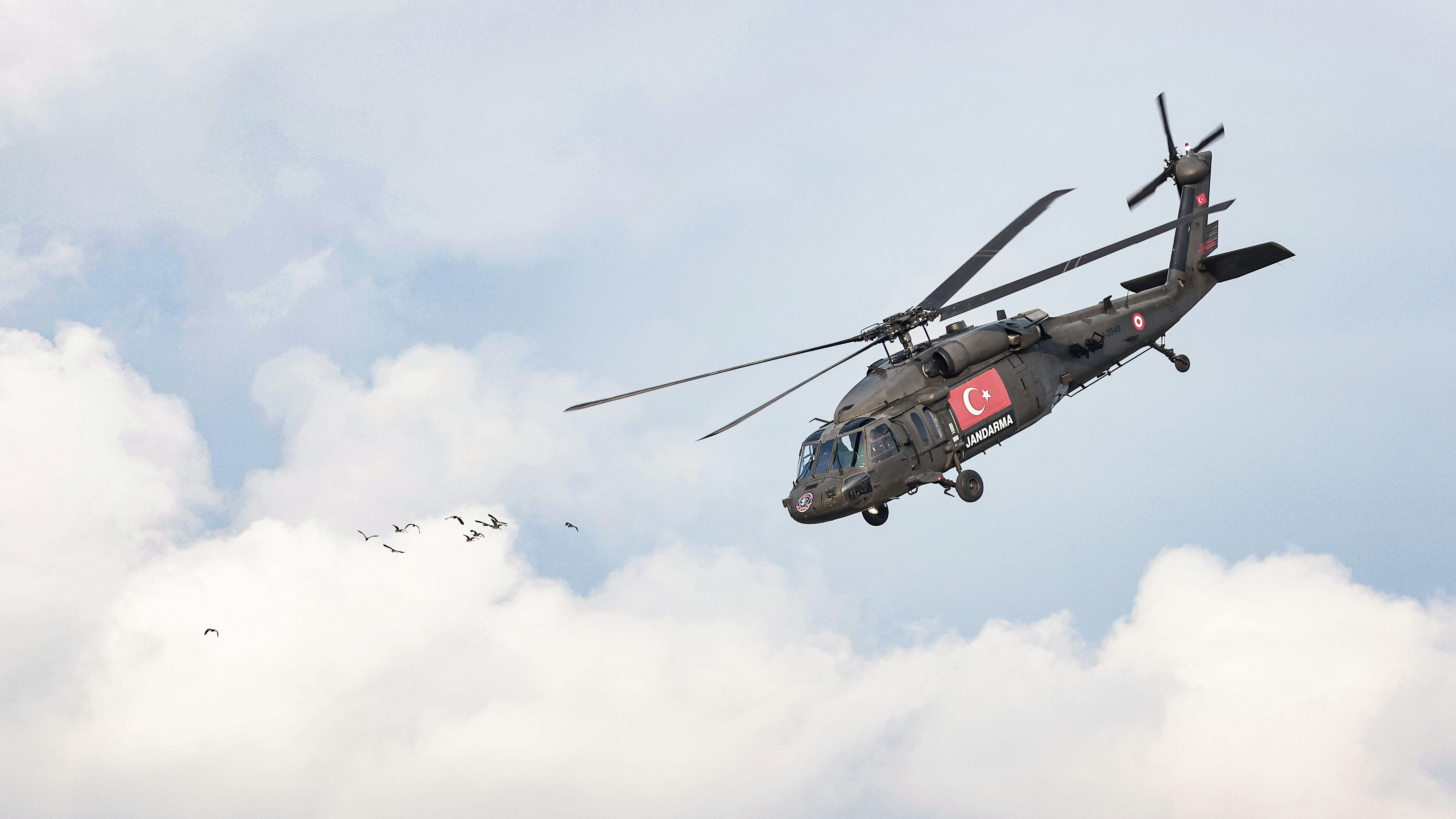A helicopter flying through a cloudy blue sky