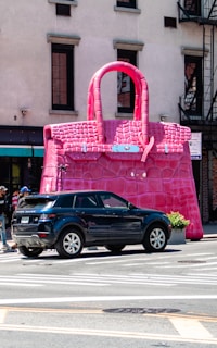 A car parked in front of a giant pink purse