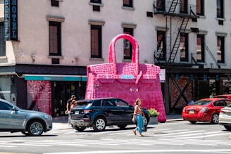 A woman crossing the street in front of a pink bag