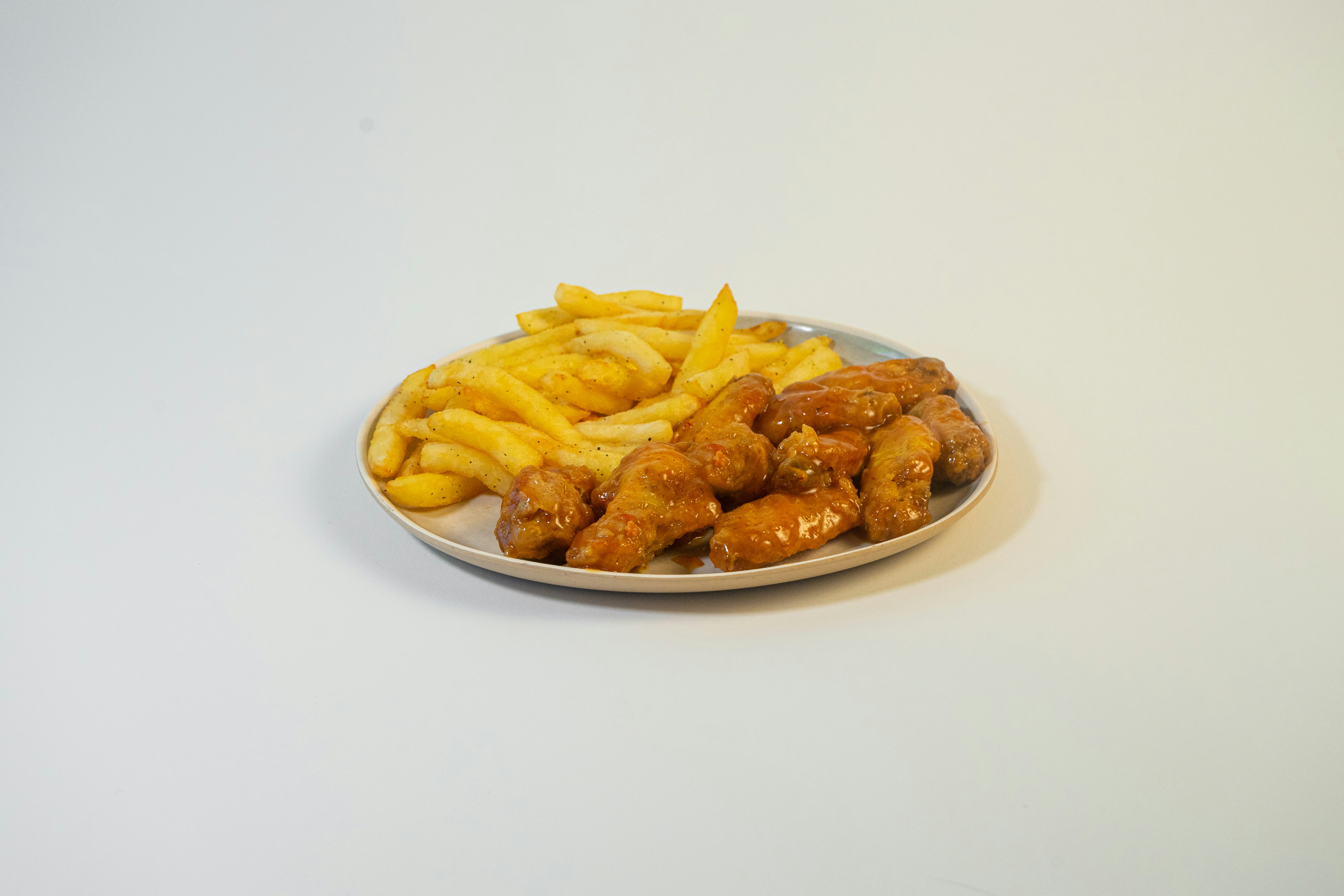 Combo Alitas: doce alitas de pollo crujientes doradas con papas fritas y bebida Frisby en bandeja