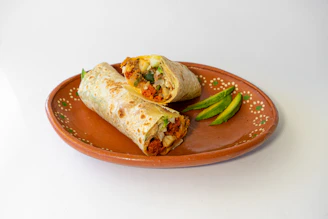 Two burritos on a plate with a side of green beans